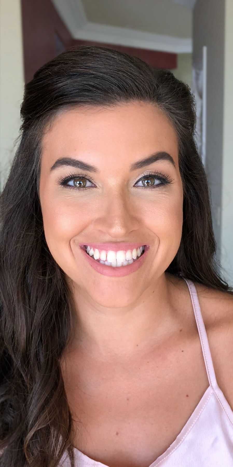 A woman in a pink tank top is smiling for the camera. Orange county hair and makeup artist.