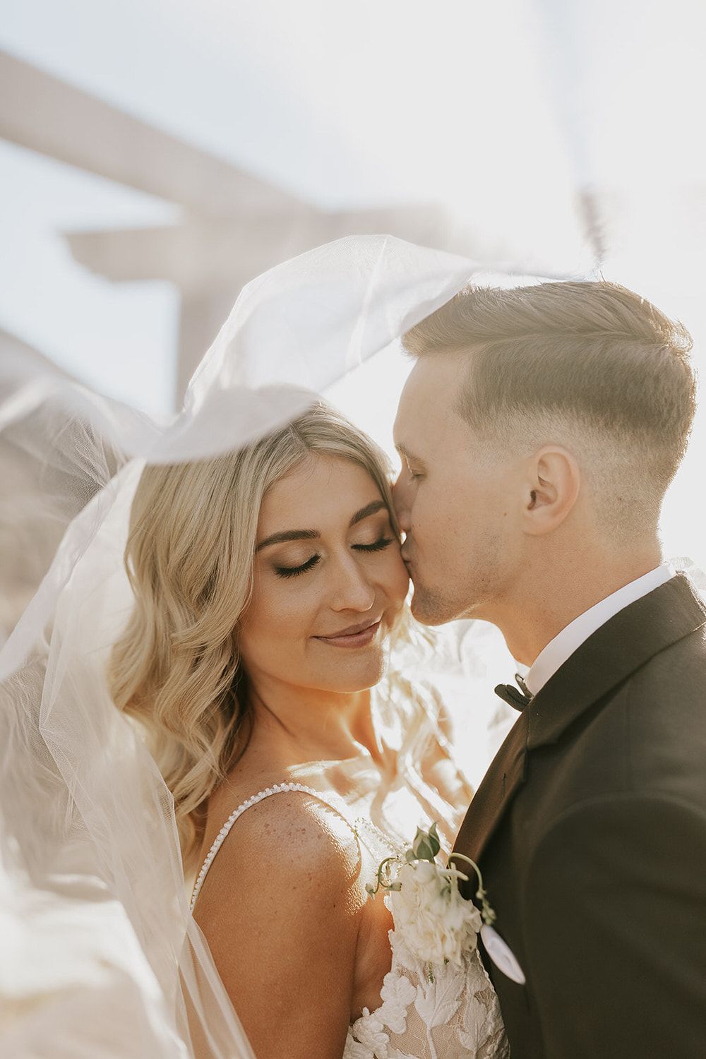 A bride and groom are kissing under a veil. Orange county hair and makeup artist.