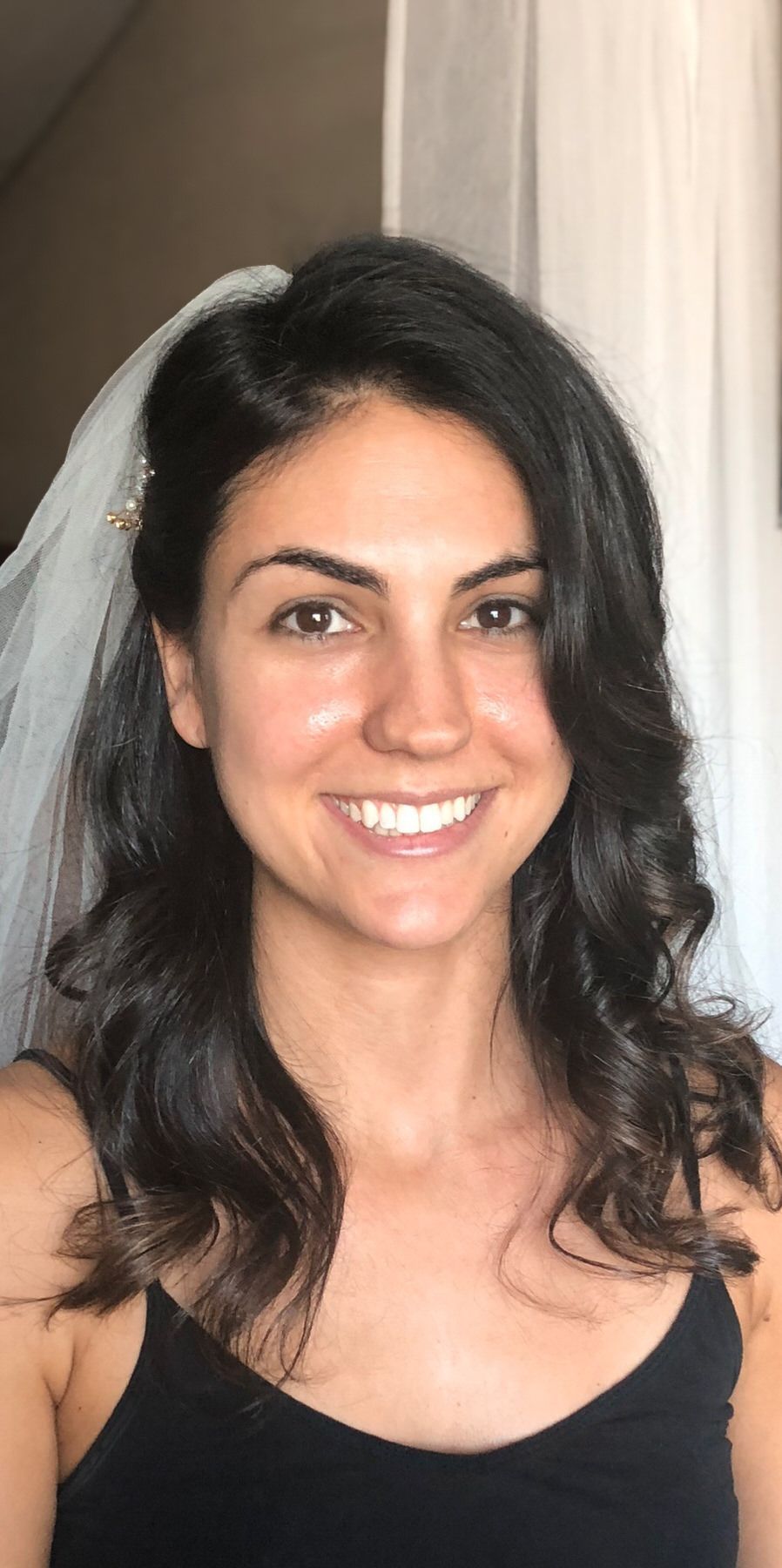 A woman wearing a veil and a black tank top is smiling. Orange county hair and makeup artist.