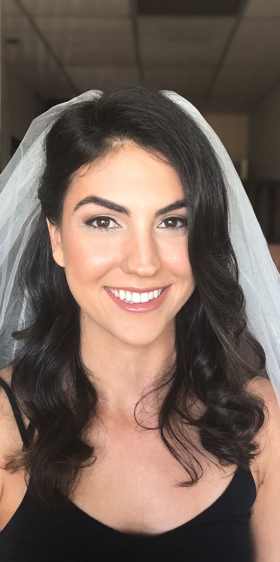 A woman wearing a veil and a black tank top is smiling. Orange county hair and makeup artist.