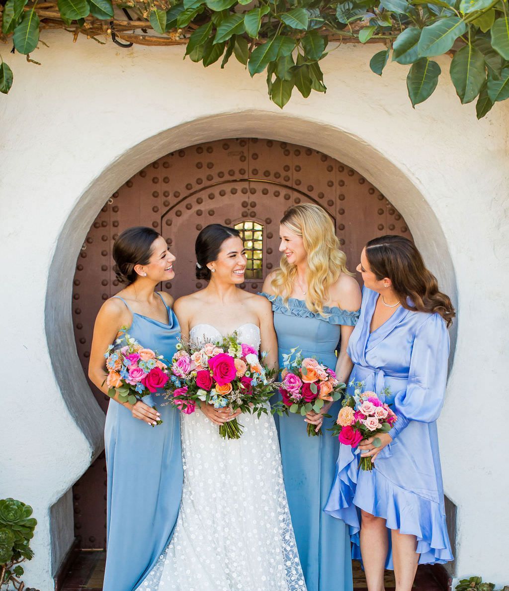 A bride and her bridesmaids are posing for a picture after getting their hair and makeup done.