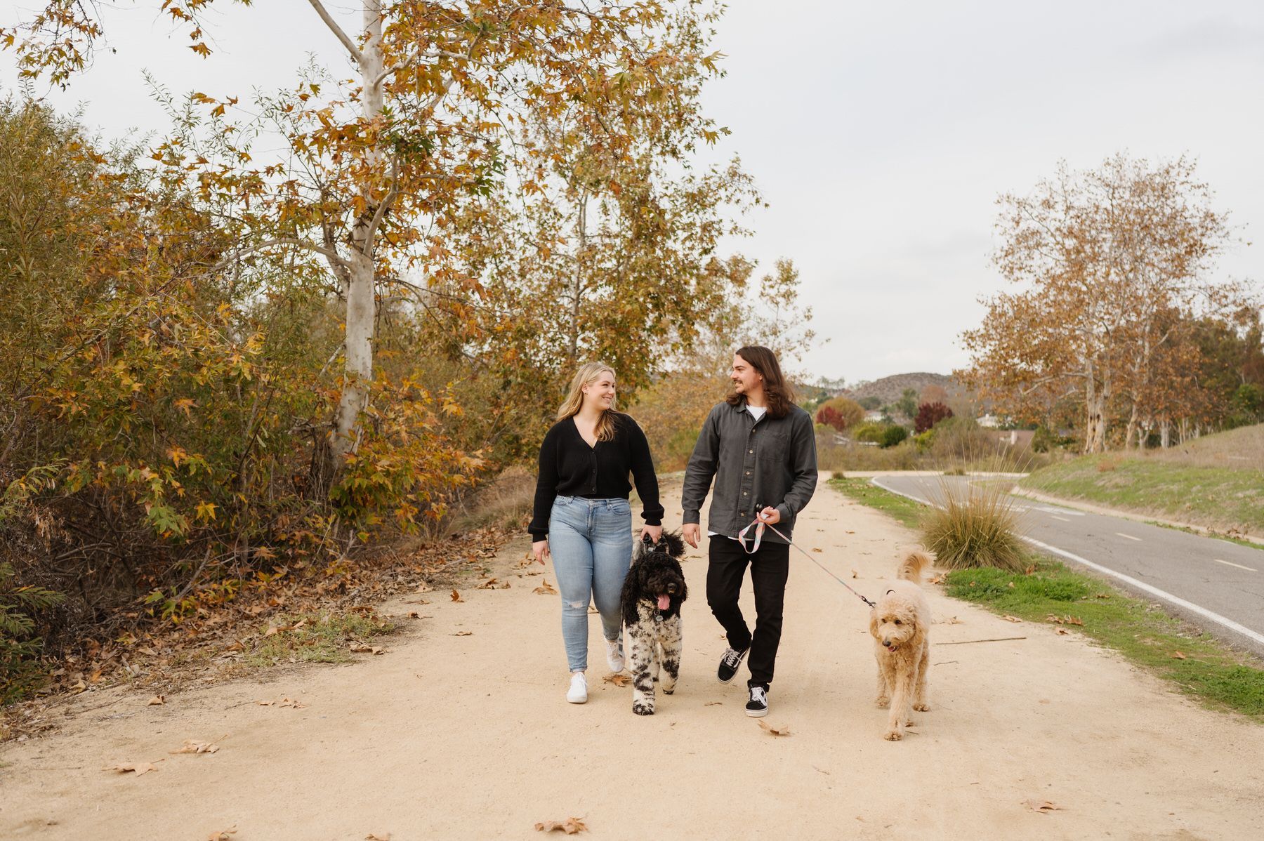 A group of people are walking a dog down a dirt path. Orange county hair and makeup artist.