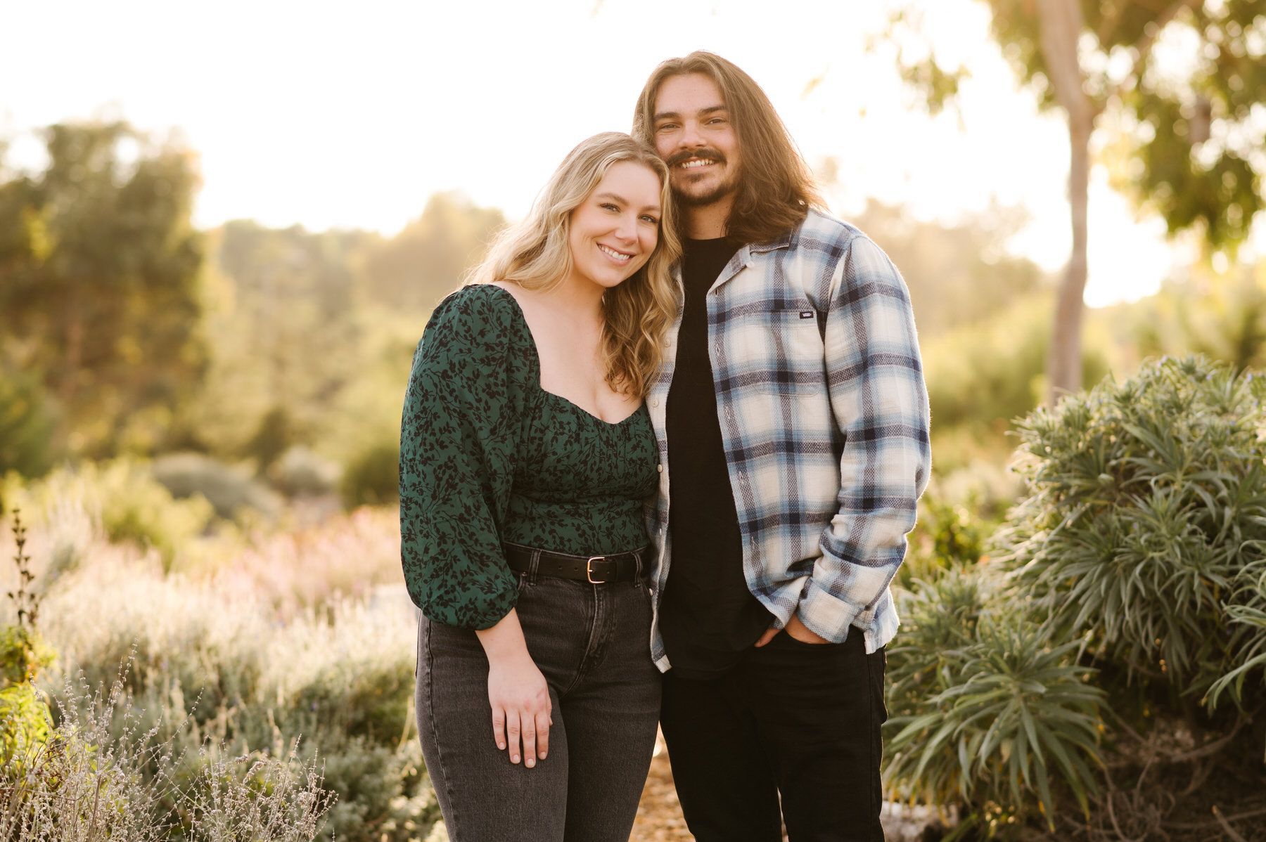 A man and a woman are standing next to each other in a field. Orange county hair and makeup artist.