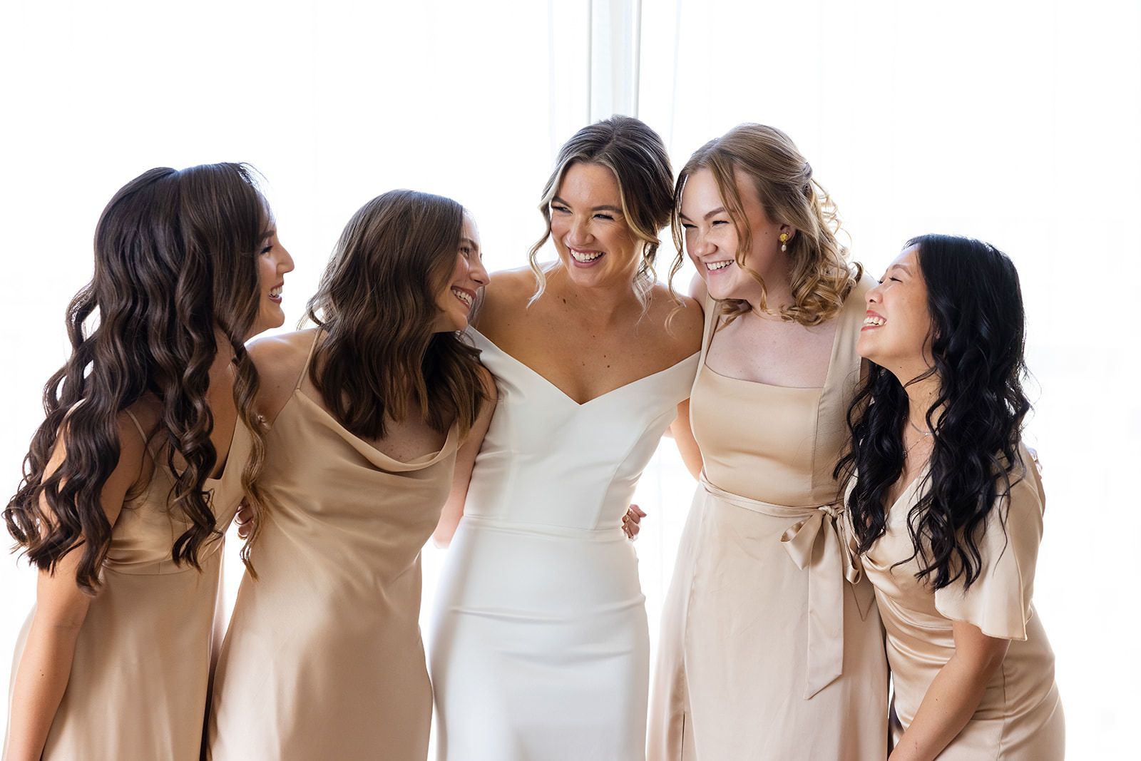A bride and her bridesmaids are posing for a picture together. Orange county hair and makeup artist.