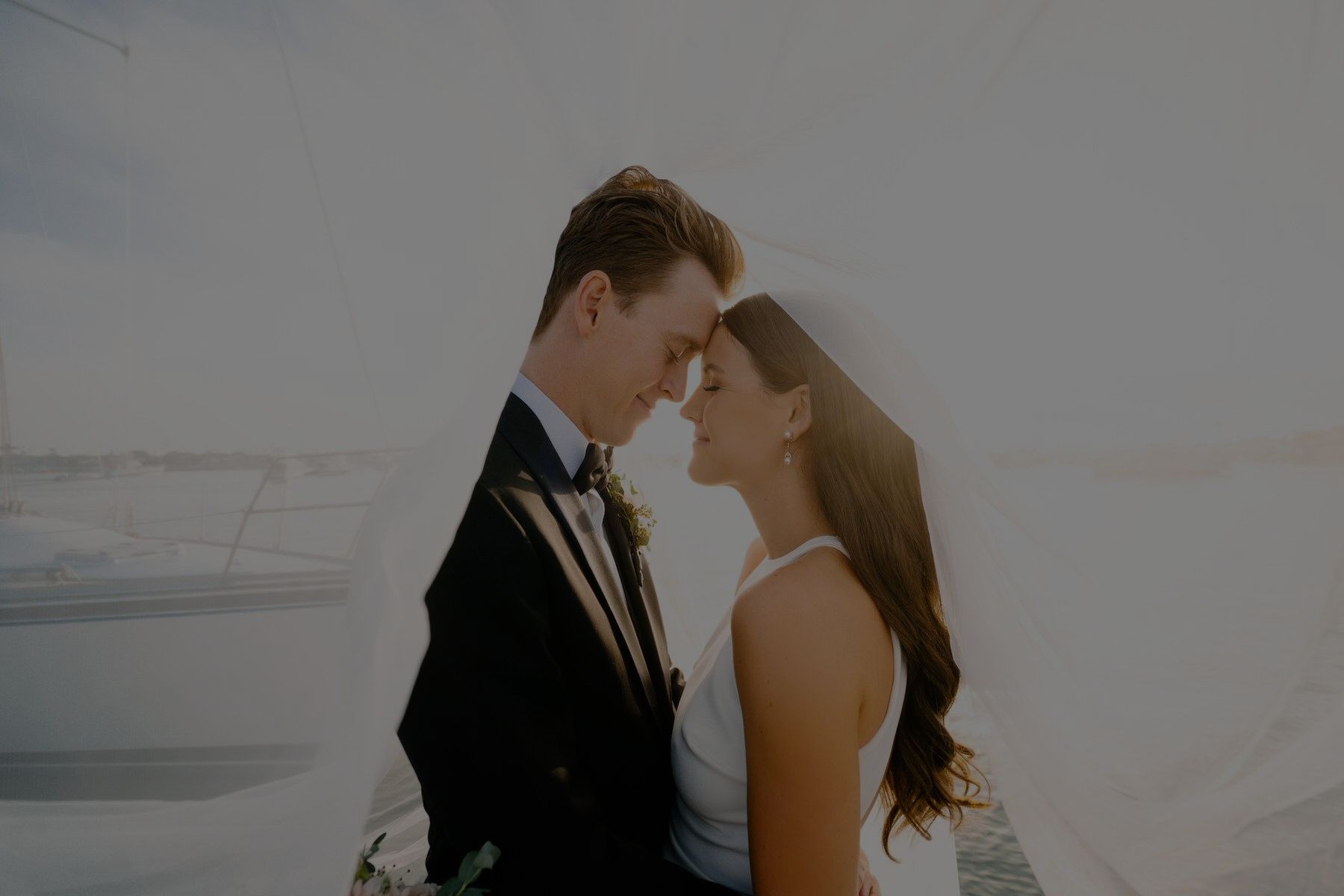 A bride and groom are standing next to each other and looking into each other 's eyes. Orange county hair and makeup artist.