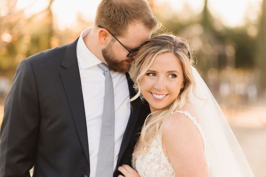 A bride and groom are posing for a picture on their wedding day. Orange county hair and makeup artist.