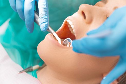 Dentista che utilizza gli strumenti per esaminare i denti del paziente.