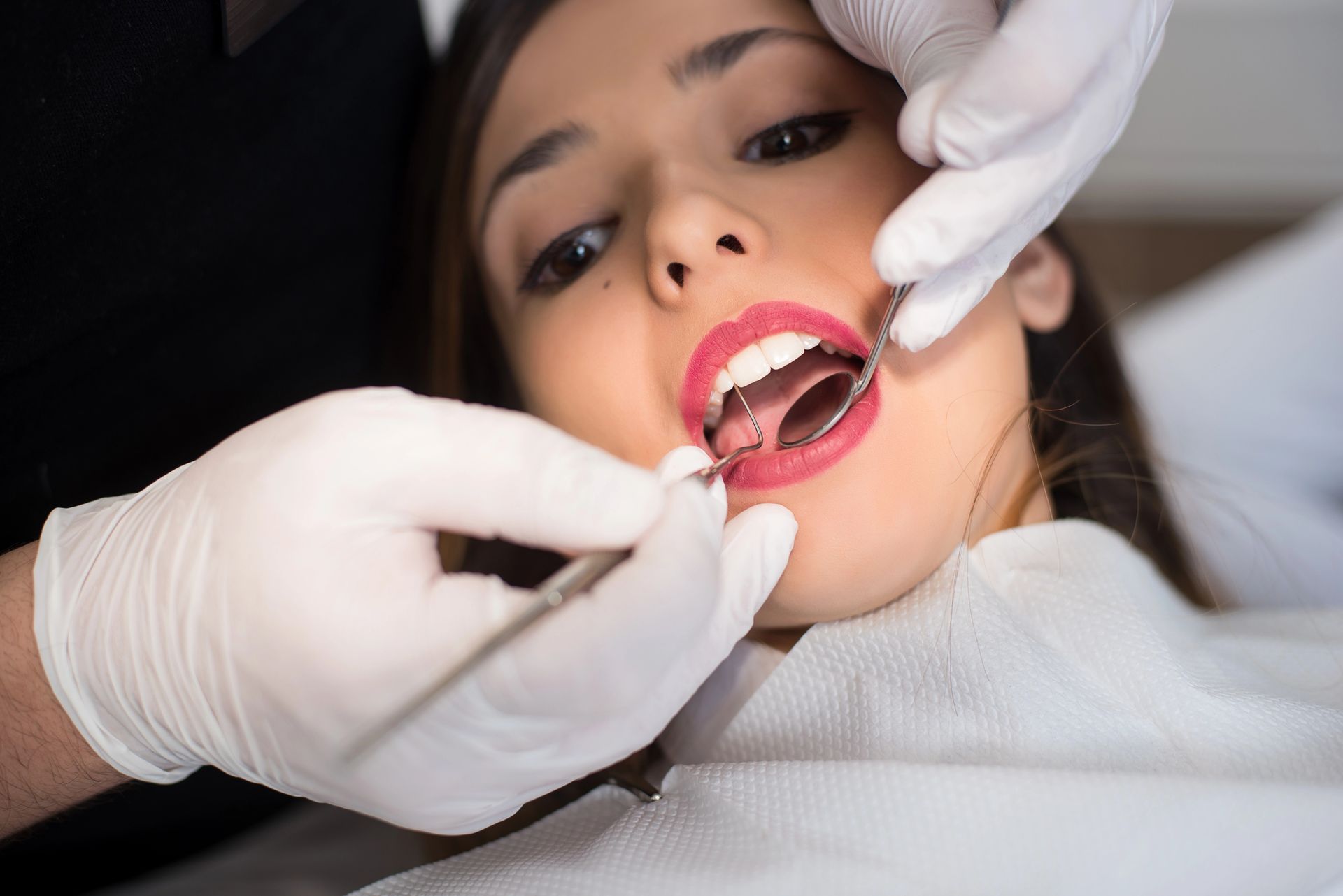 Persona sottoposta a visita dentistica, bocca aperta, dentista che utilizza degli strumenti.
