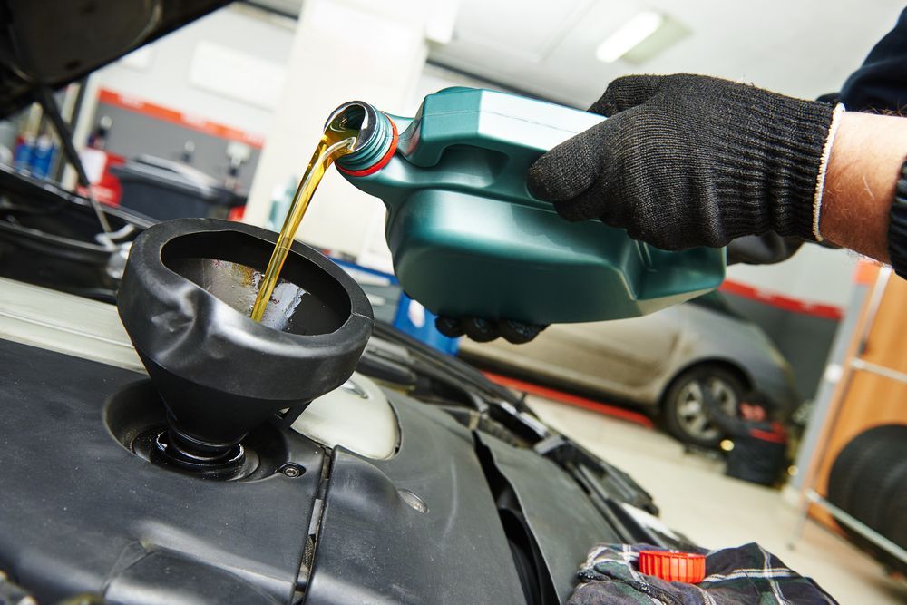 Gloved Hand Pouring Motor Oil From a Green Bottle — Precision Tuning in Trinity Beach, QLD