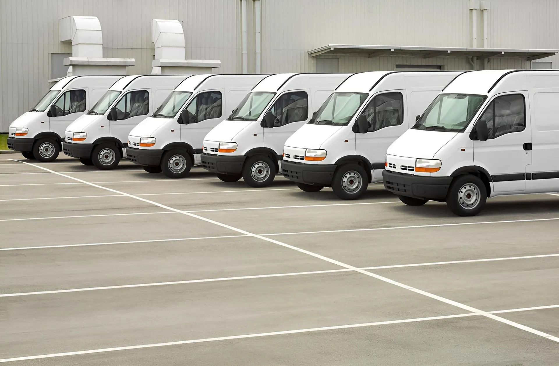 White Vans Parked in A Row in A Paved Lot, with A Light Gray Building — Precision Tuning in Bungalow, QLD