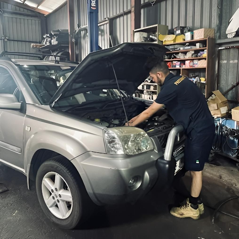 Mechanic Working on The Engine of A Silver Suv in A Garage with The Hood Open — Precision Tuning in Bungalow, QLD
