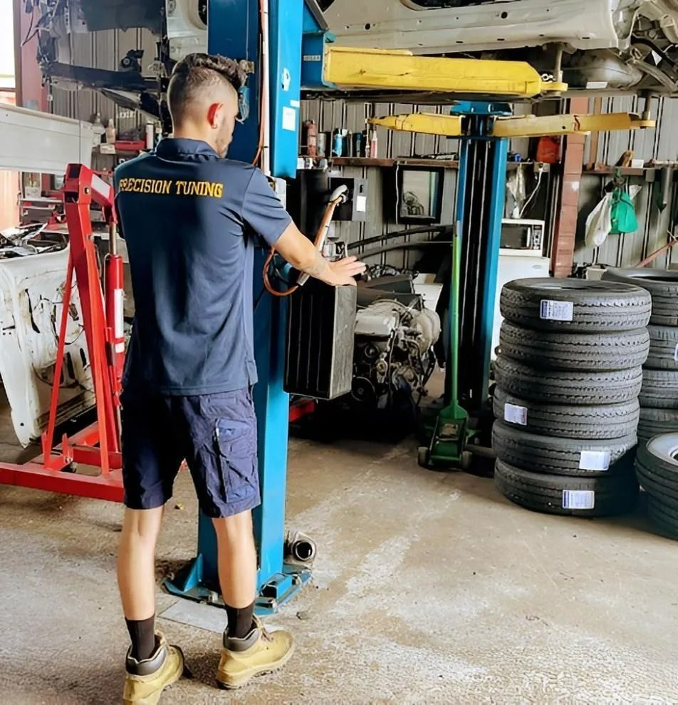 Mechanic in Blue Shirt and Shorts Using a Car Lift in A Garage — Precision Tuning in Cairns, QLD