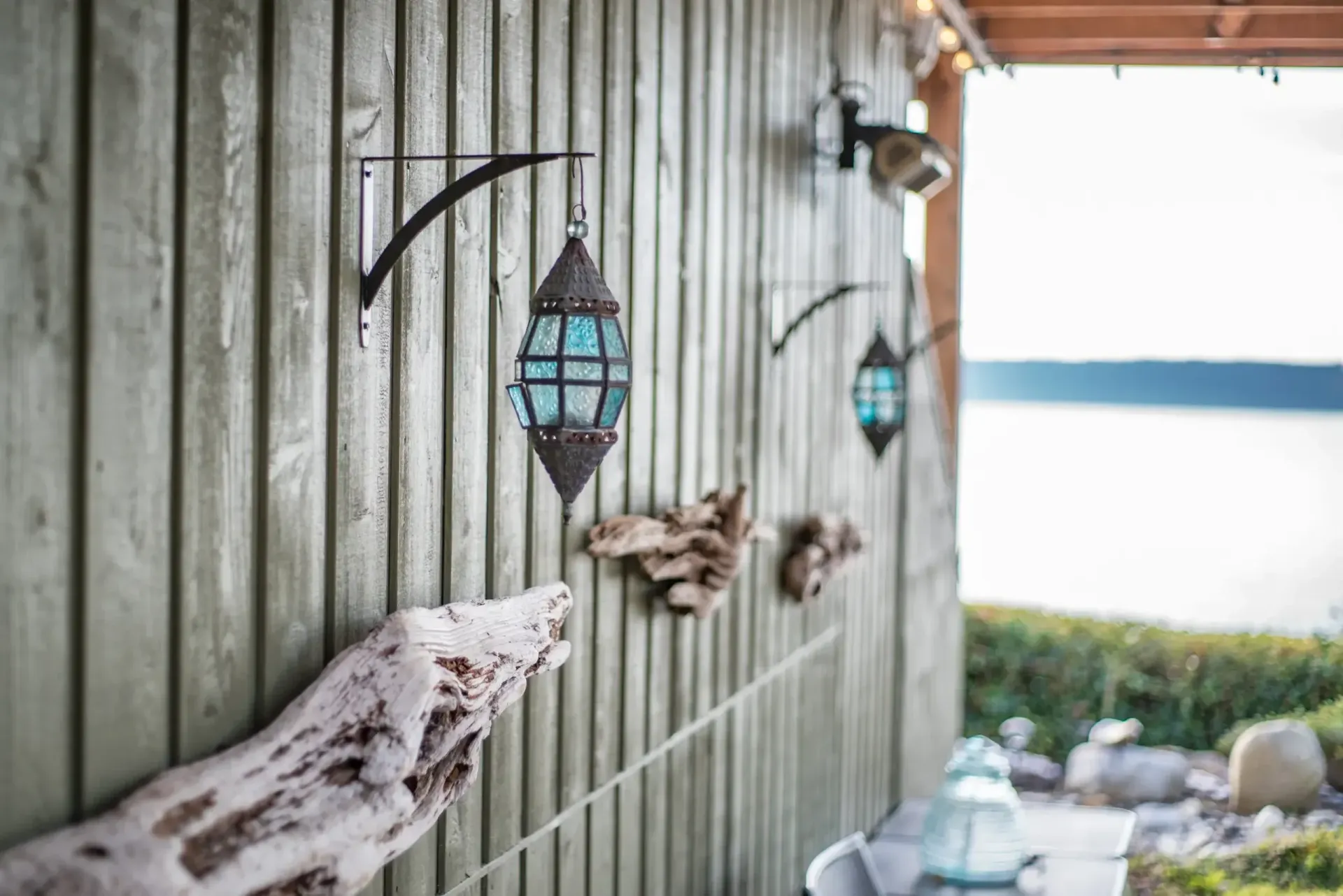 A wooden wall with lanterns and driftwood on it.