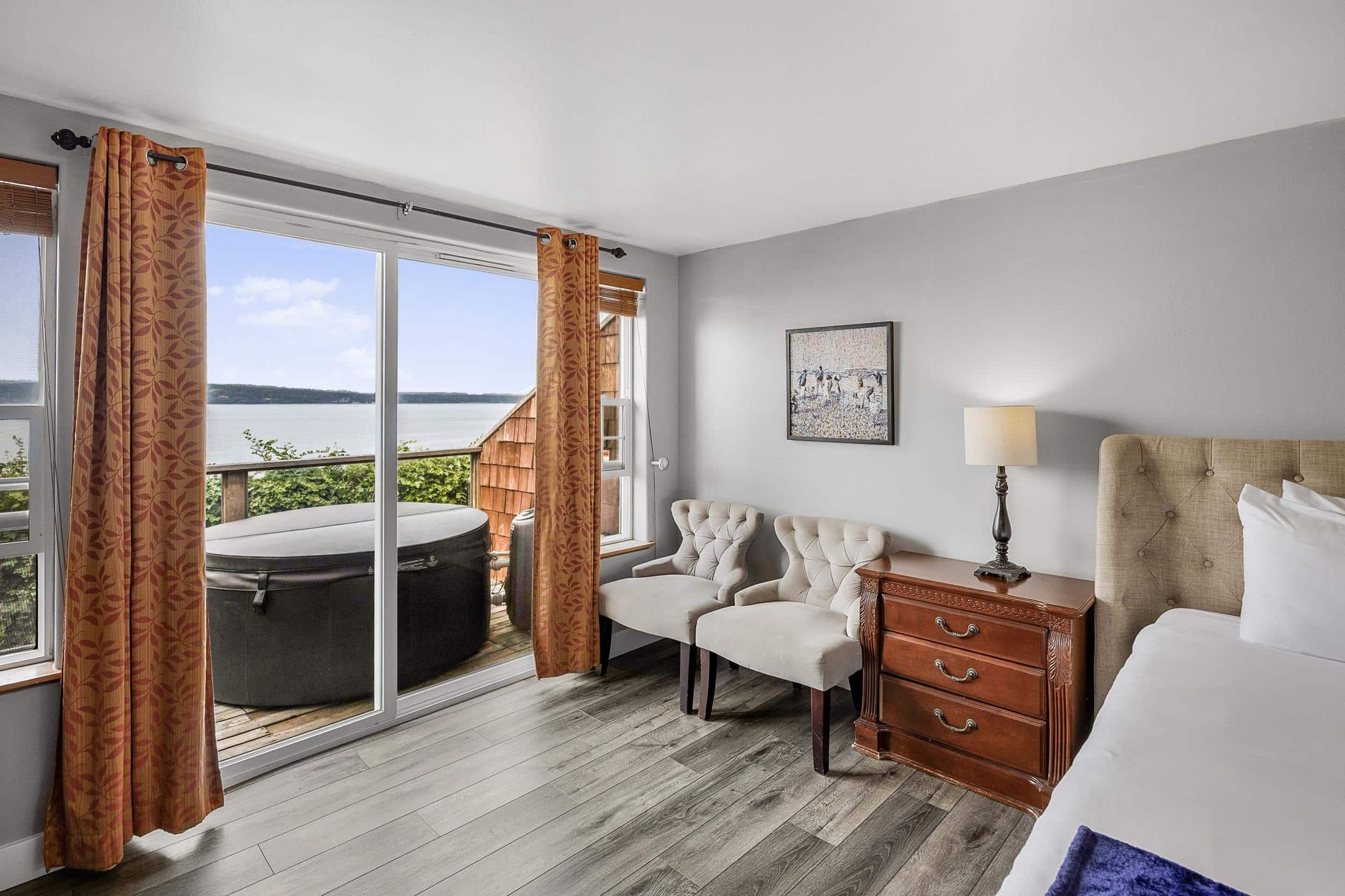 A wooden deck with tables and chairs under a pergola overlooking the ocean.