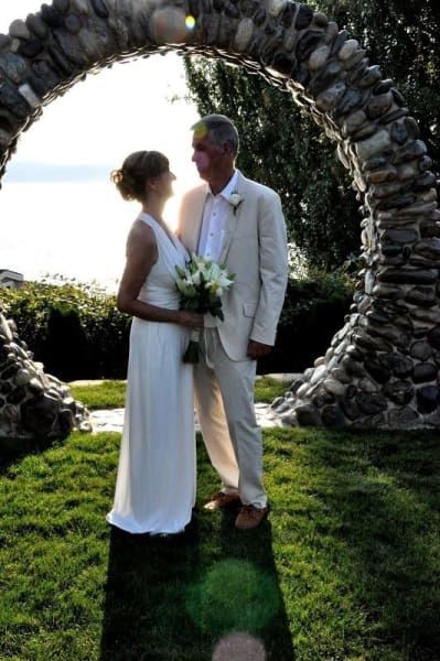 A bride and groom standing under a stone arch