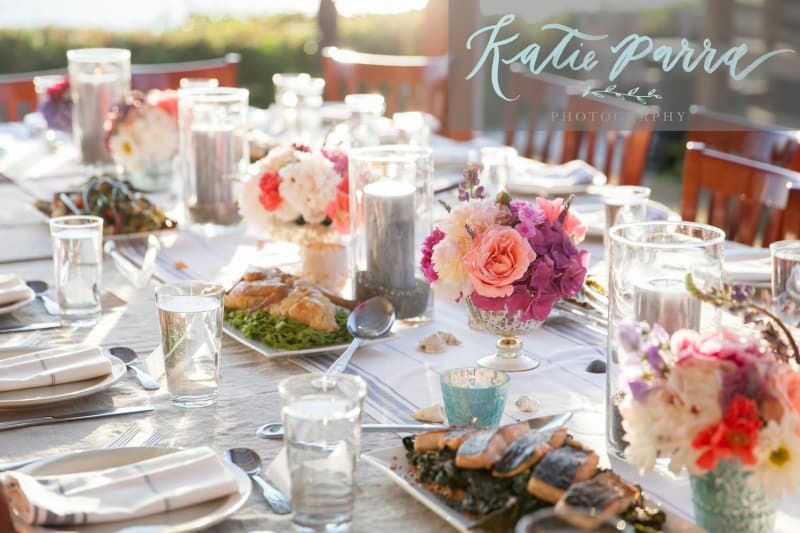A long table with plates , glasses , and flowers on it.