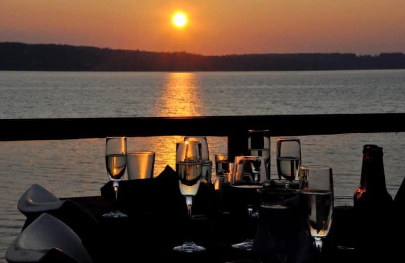 A sunset over a body of water with wine glasses on a table