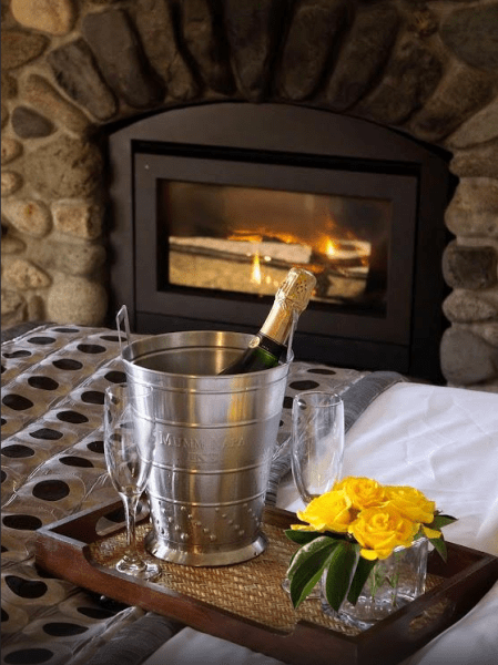 A bucket of champagne sits on a tray in front of a fireplace