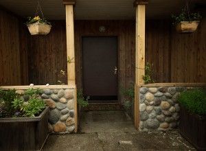 The front door of a house with a stone wall and planters.