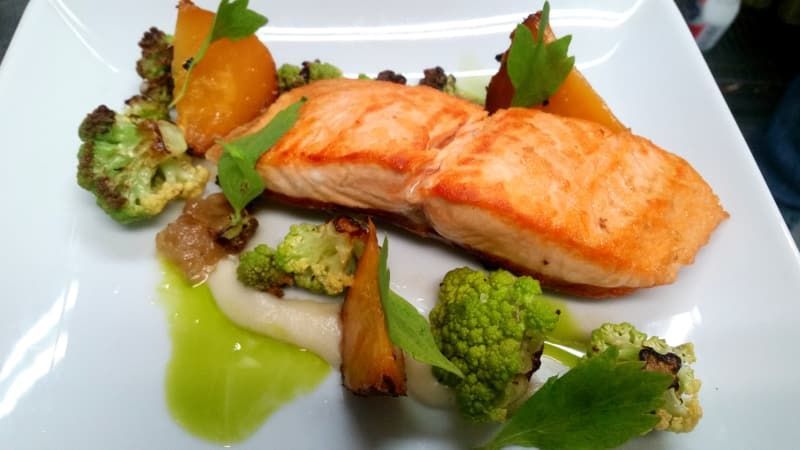 A white plate topped with a piece of salmon and vegetables