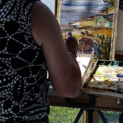 A woman in a black and white dress is painting on an easel
