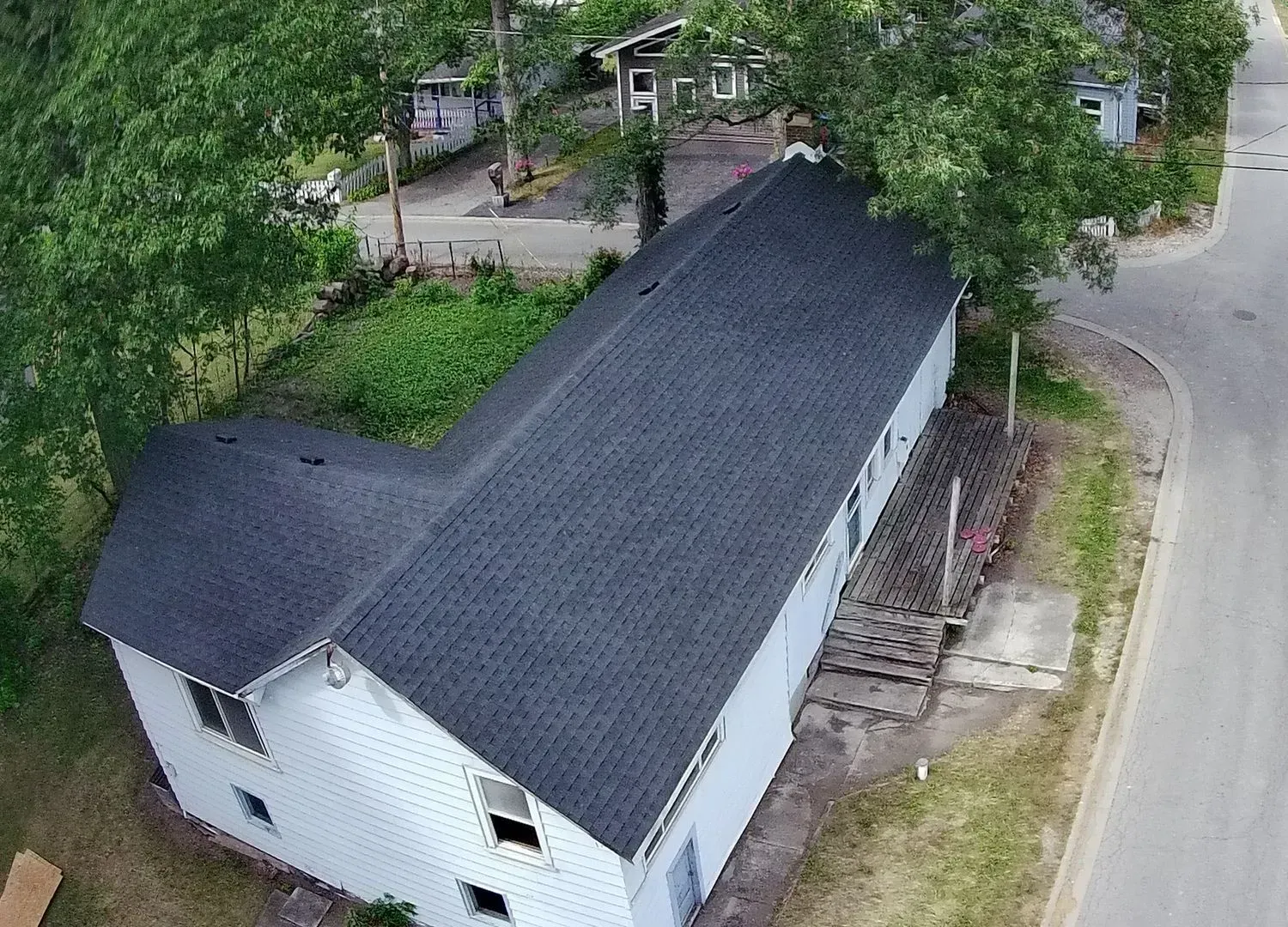 An aerial view of a white house with a black roof.