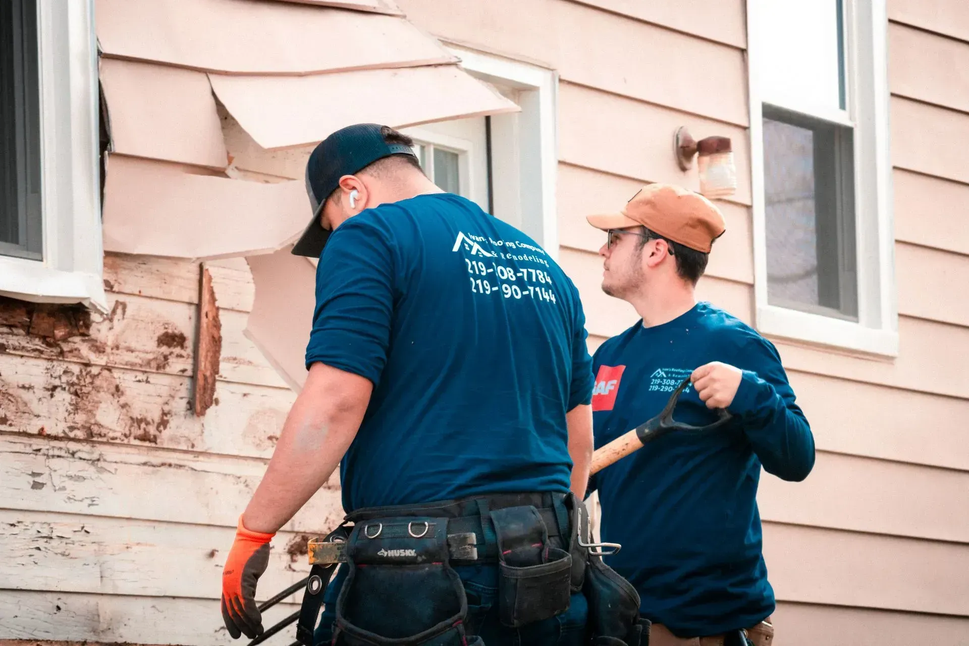 Two men are working on the side of a house.
