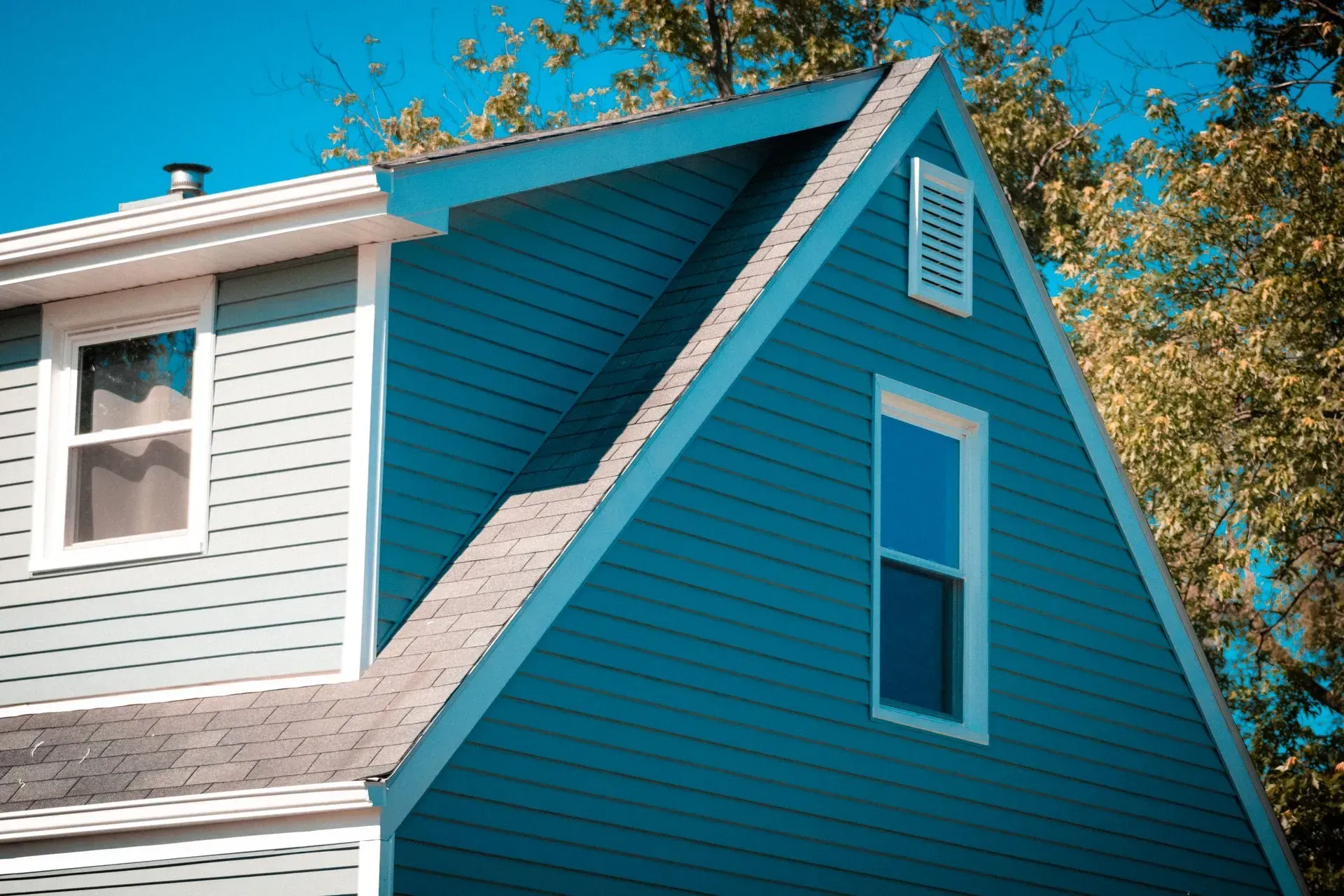 A blue and white house with a triangle shaped roof.