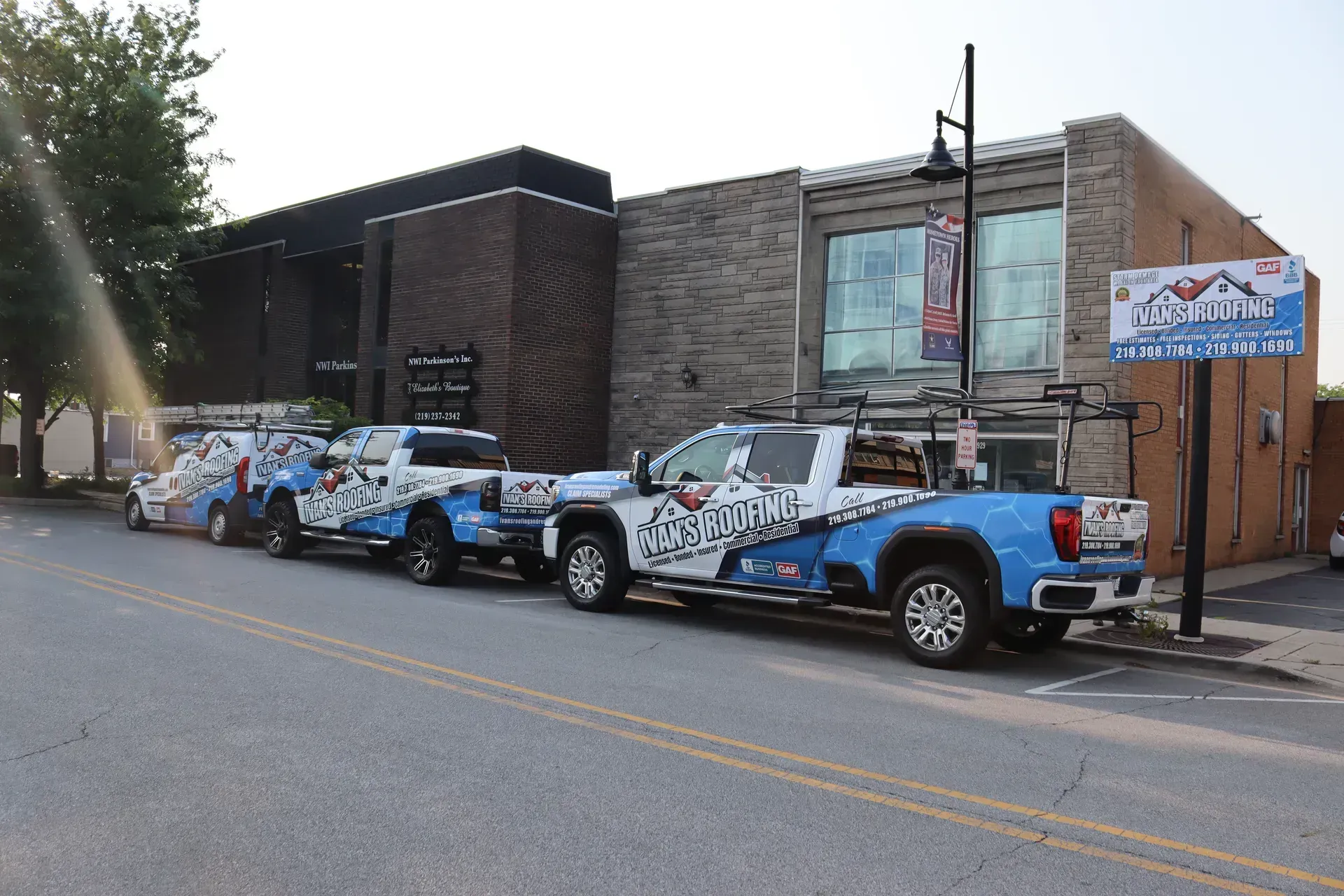 A row of blue trucks are parked in front of a building.