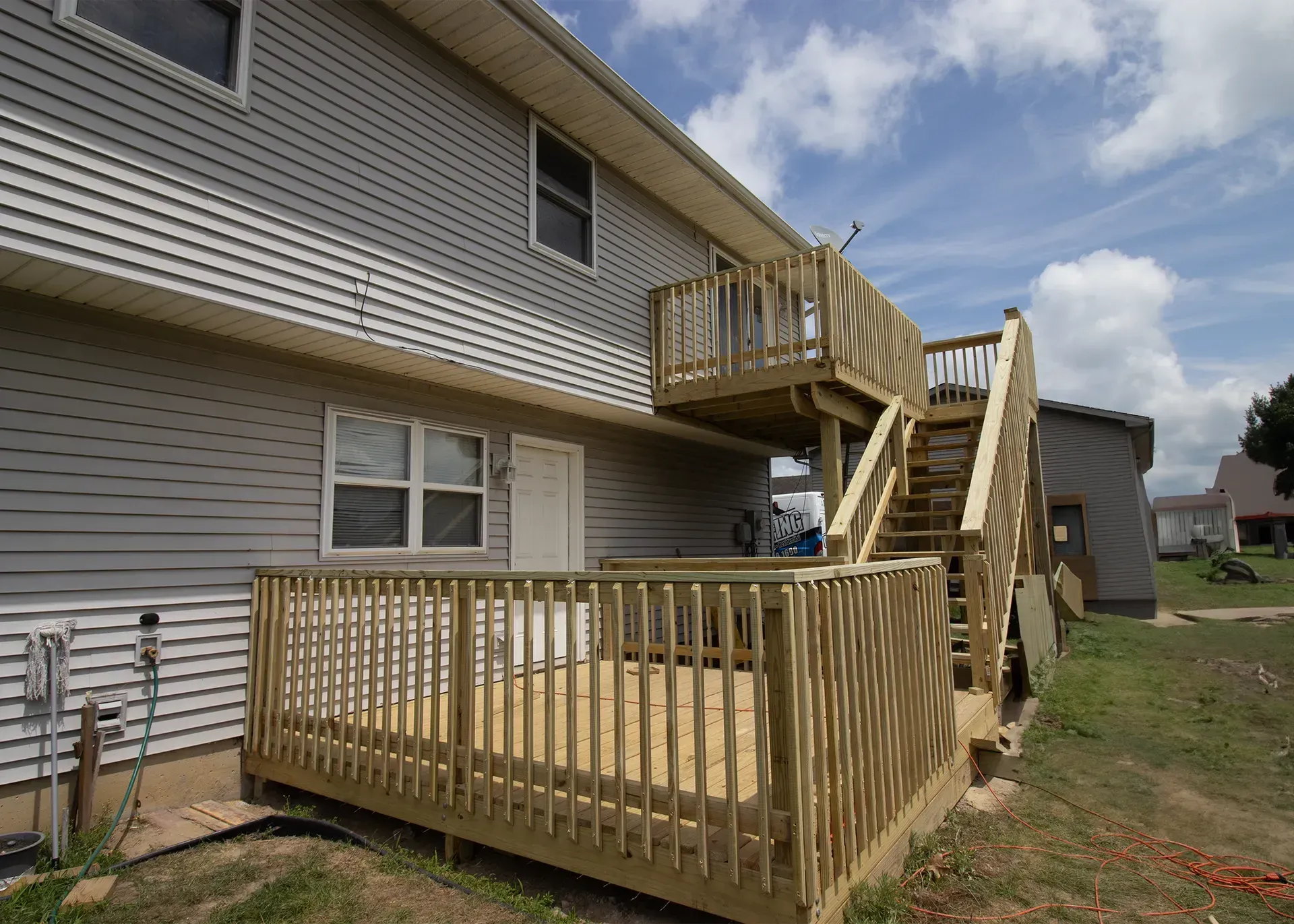 The back of a house with a wooden deck and stairs.