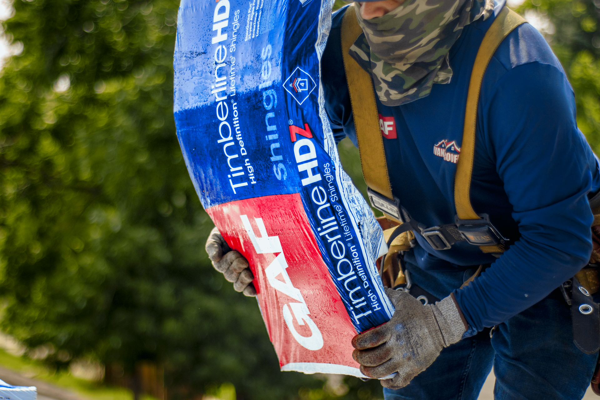 A man in a blue shirt is holding a red and blue bag.