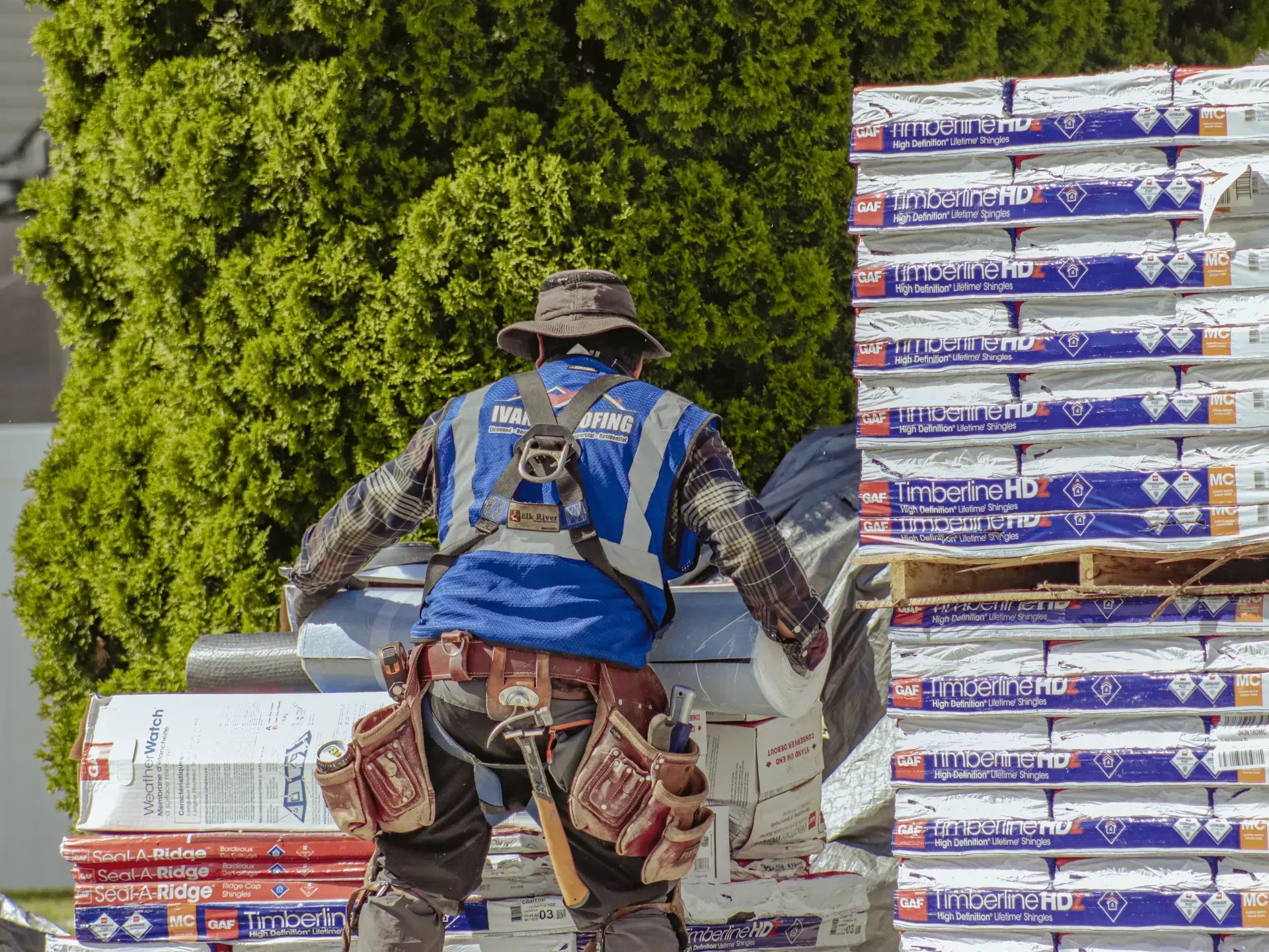 A construction worker is standing in front of a stack of boxes.
