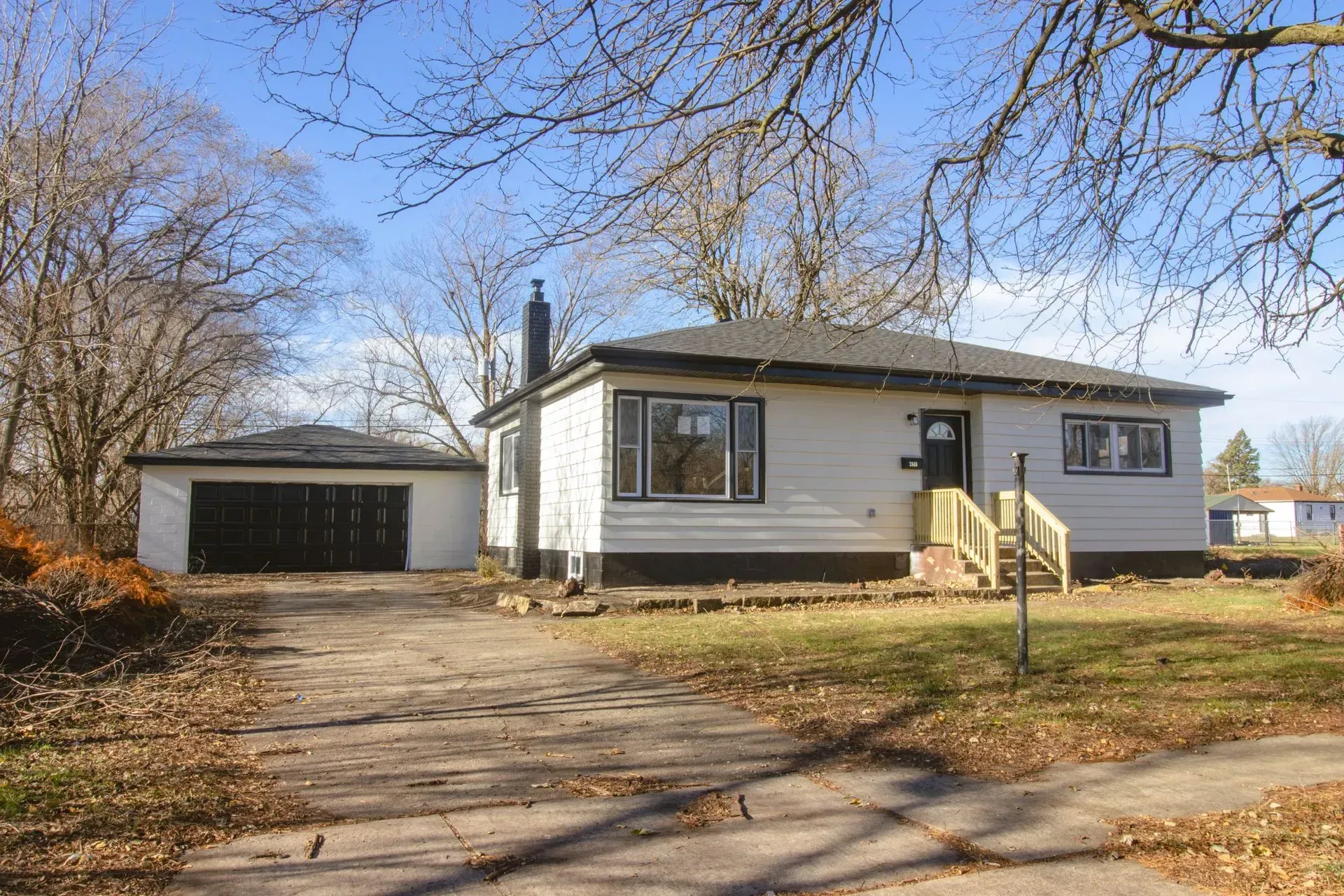 A white house with a garage and a driveway in front of it.
