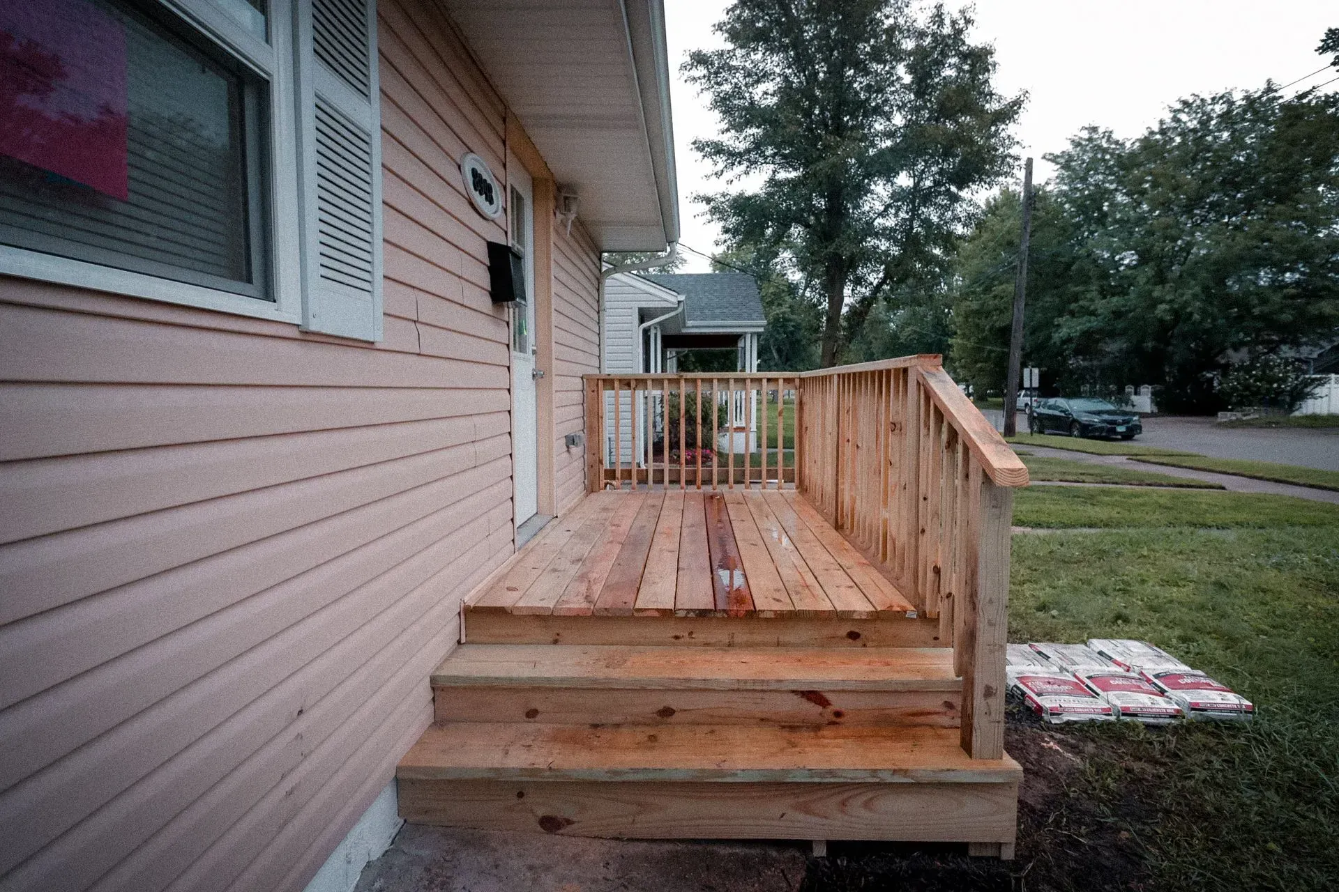 A pink house with a wooden deck in front of it