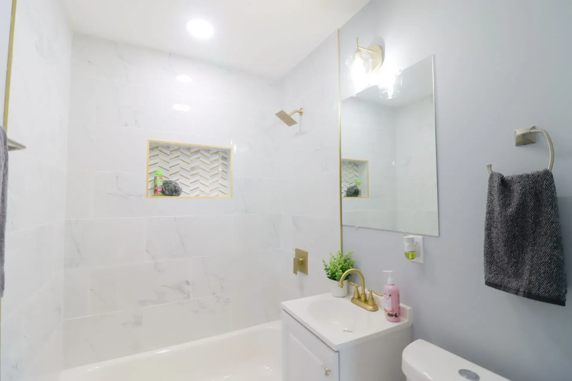 A bathroom with a sink, toilet, shower and mirror.