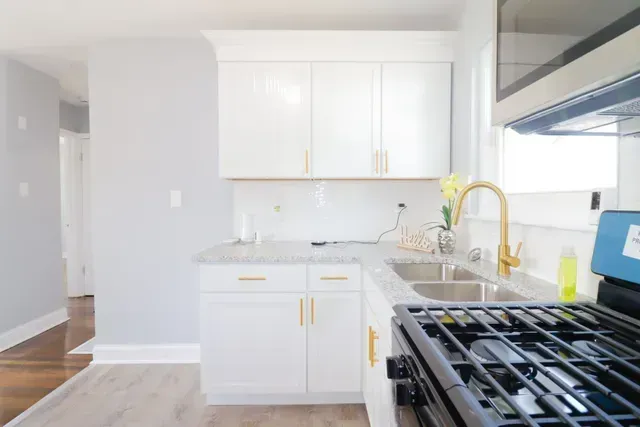 A kitchen with white cabinets, a stove and a sink.