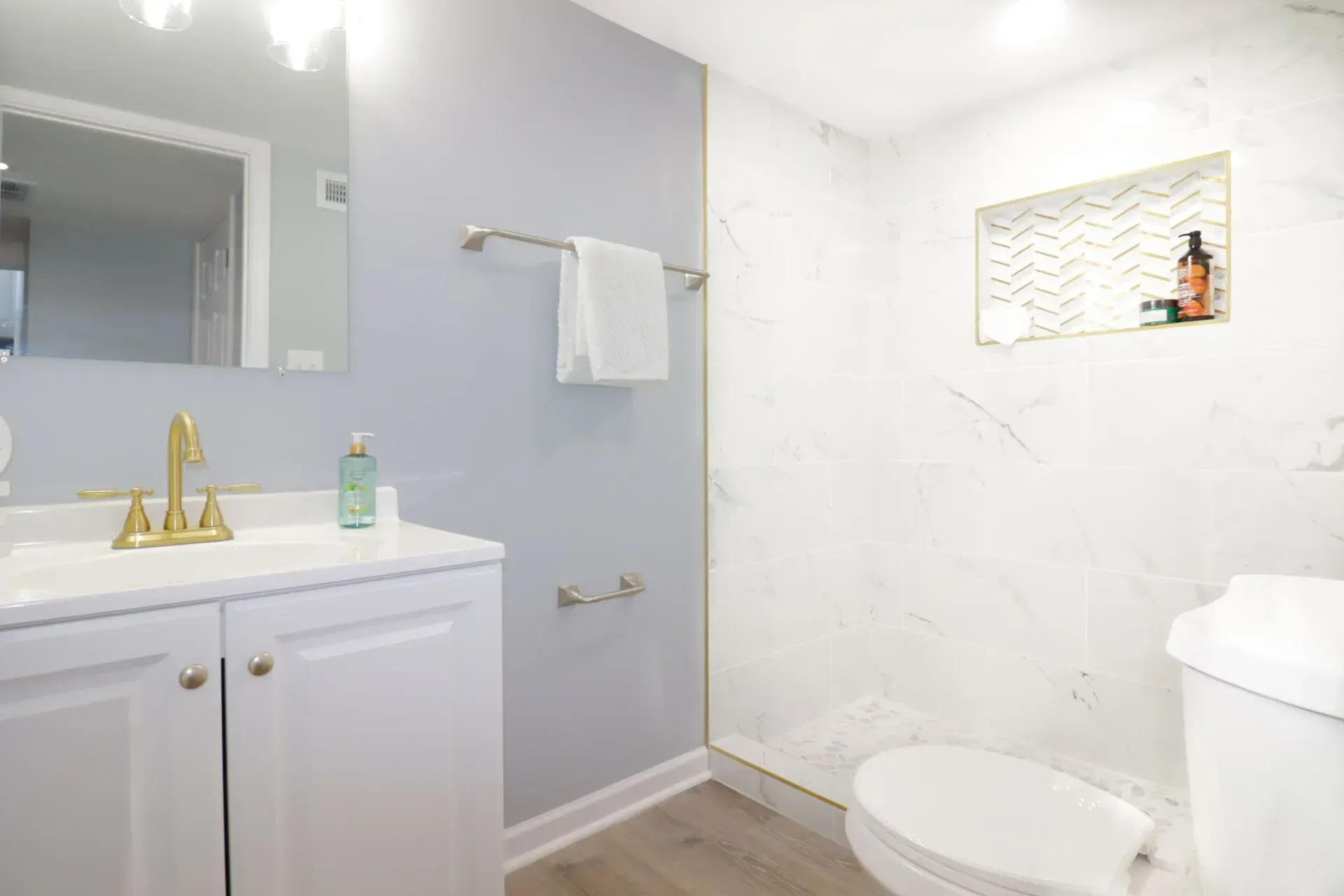 A bathroom with a toilet, sink, mirror and walk in shower.