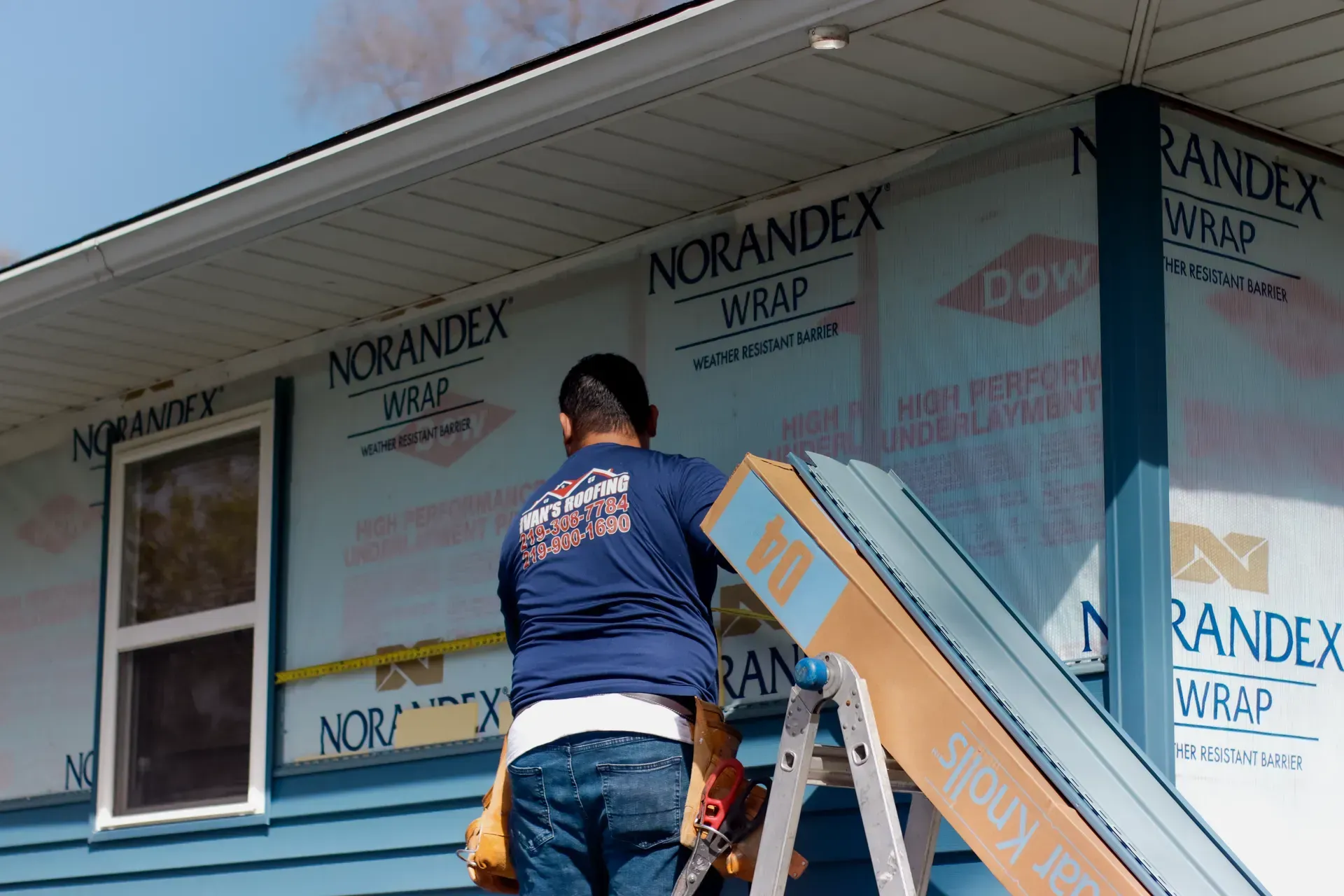 A man is standing on a ladder in front of a house.