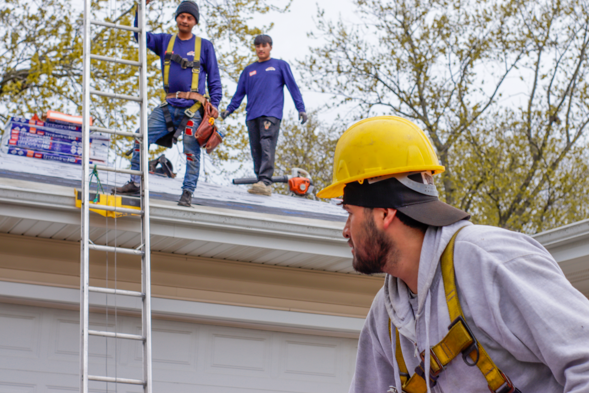 A group of construction workers are working on the roof of a house.