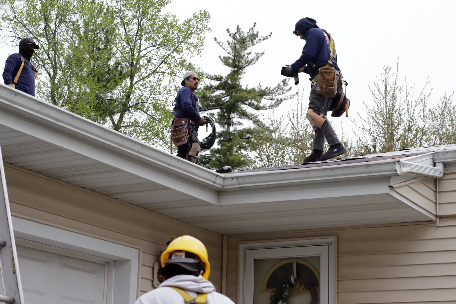 A group of men are working on the roof of a house.