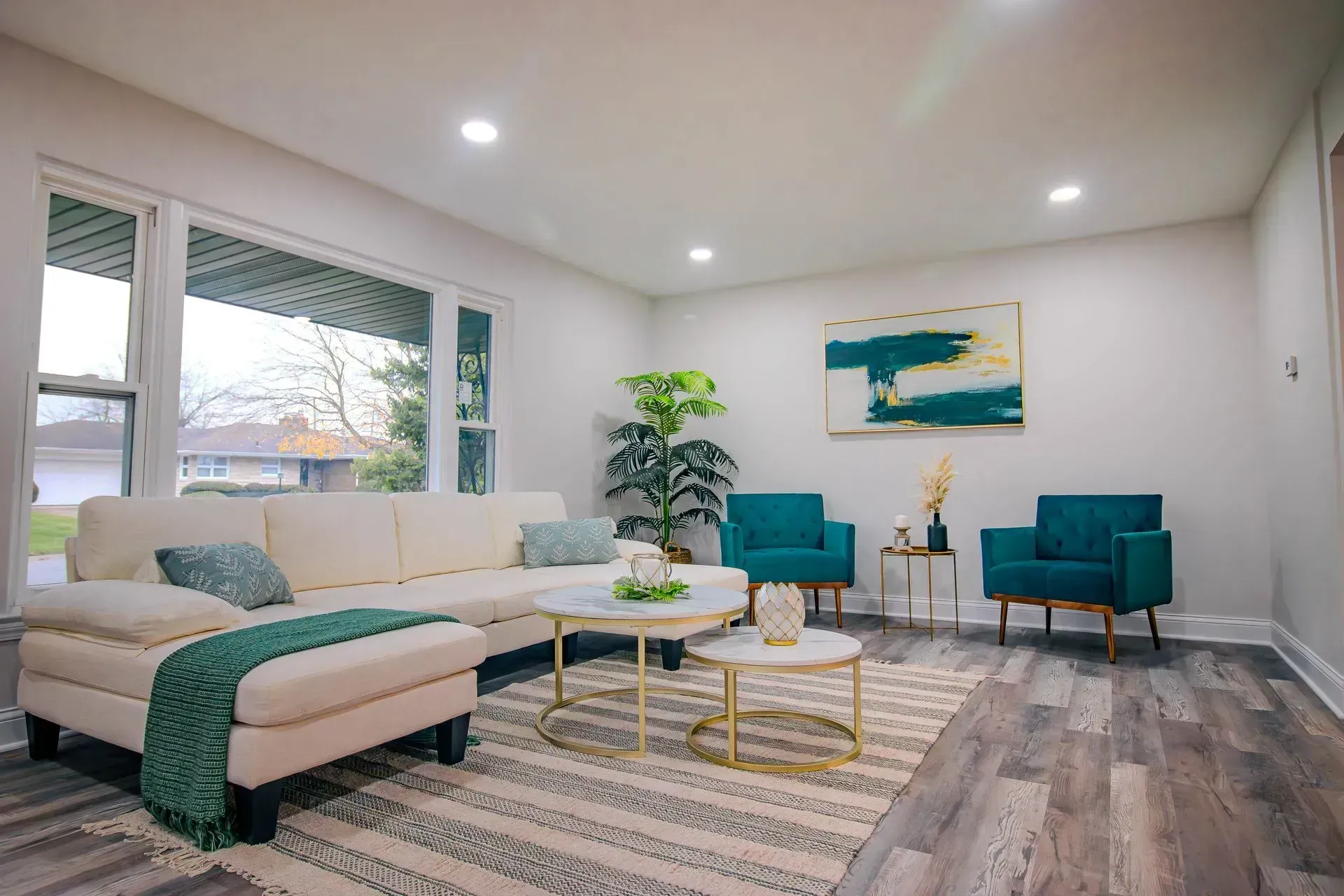 A living room with a couch , chairs , tables and a rug.