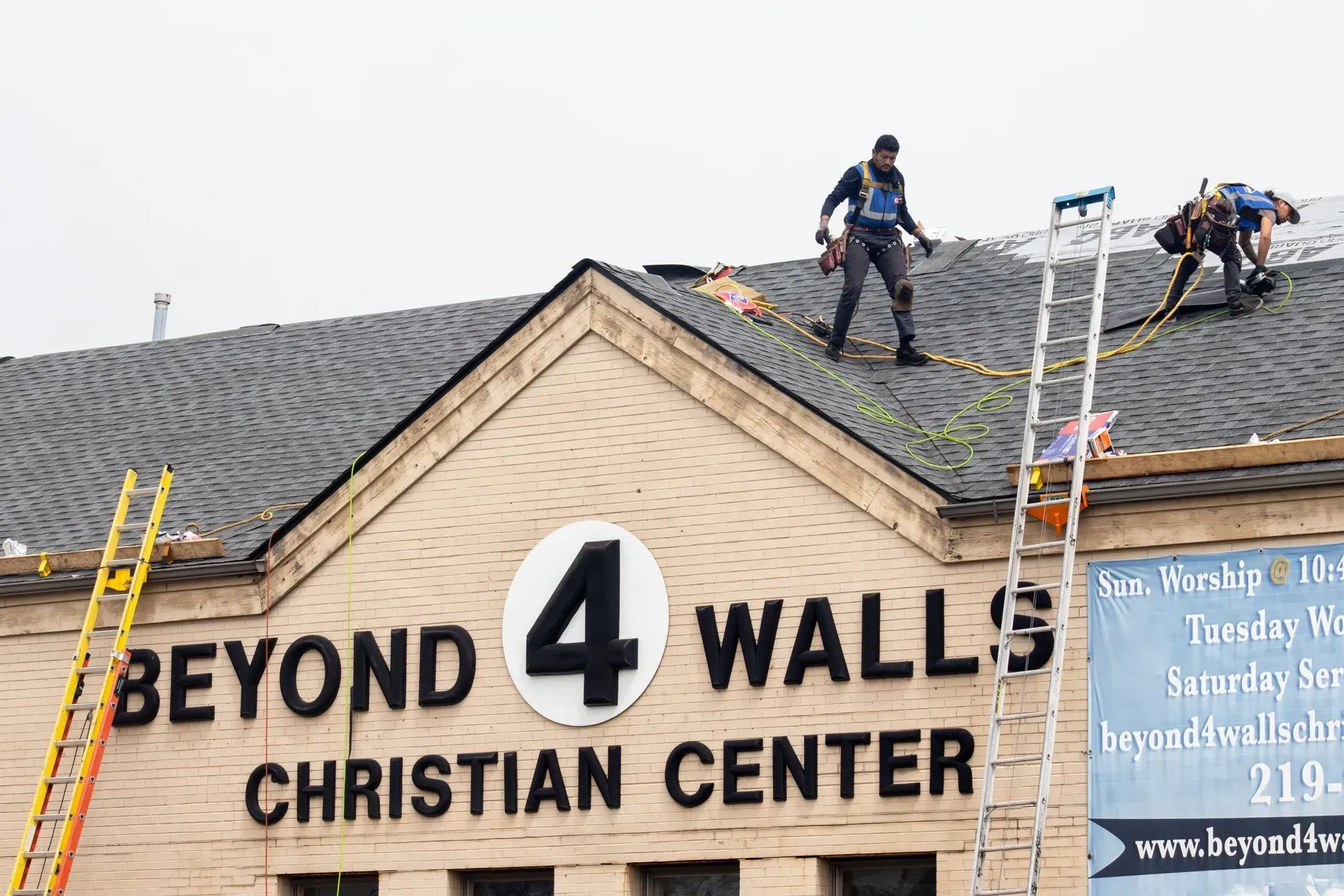 Two men are working on the roof of the beyond 4 walls Christian center.