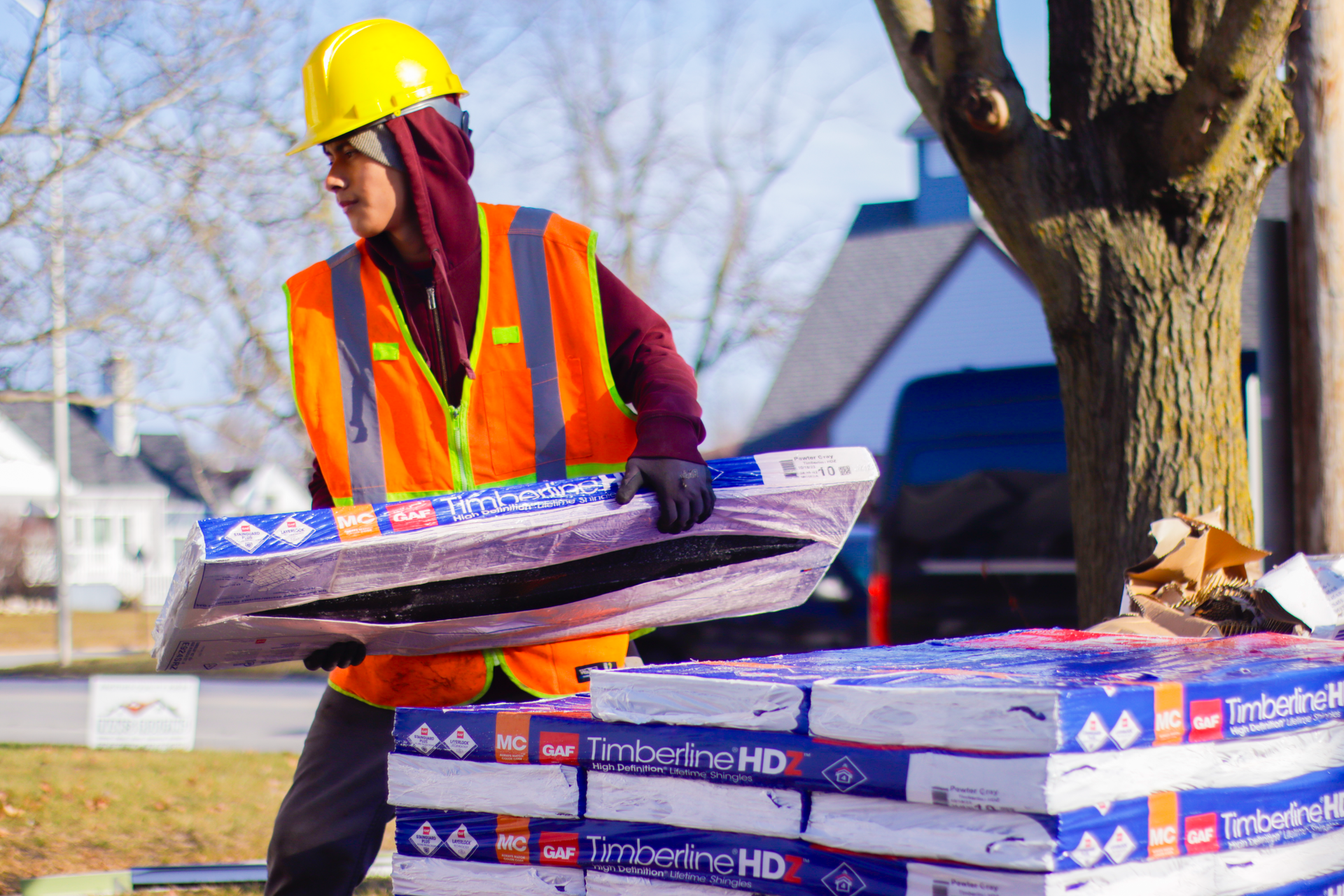 A construction worker is carrying a stack of boxes on a construction site.