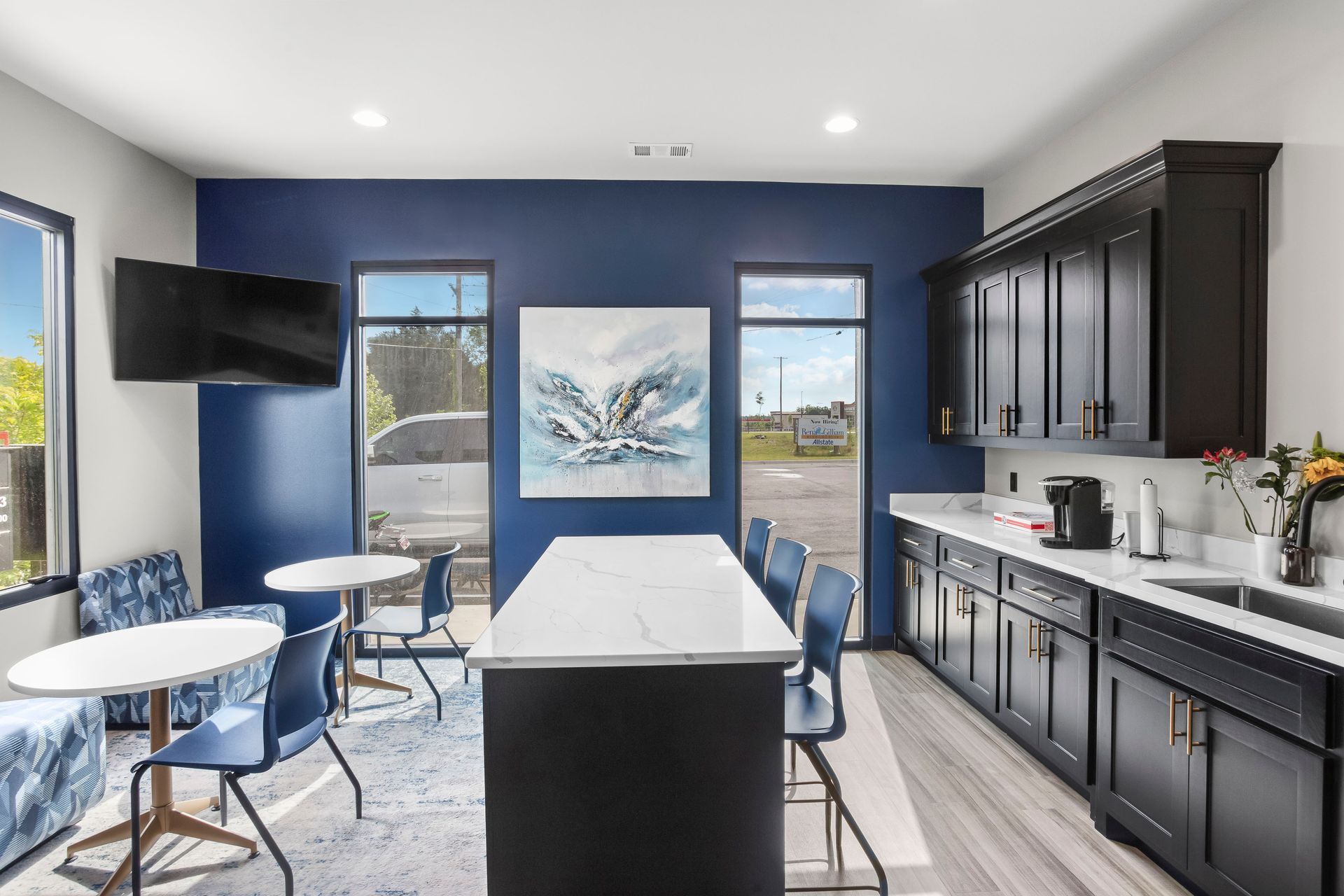 Modern kitchen with navy blue cabinets, white countertops, and seating area.