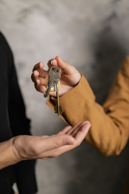 Person handing keys to another person; close-up shot.