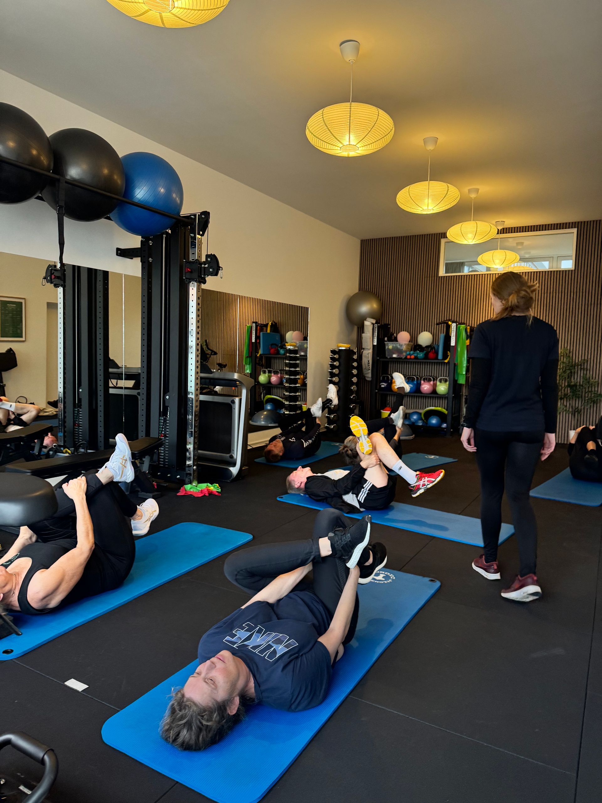 En gruppe kvinder laver øvelser med pilatesbolde i et fitnesscenter.