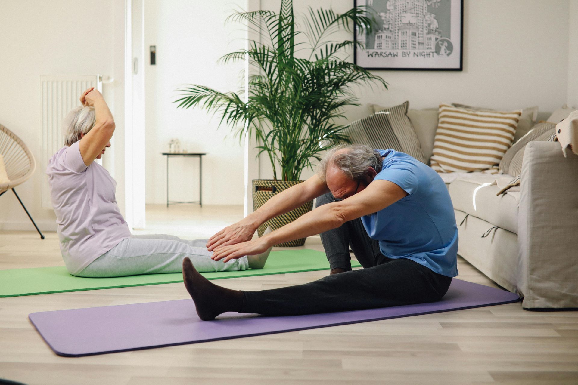 En mand og en kvinde strækker sig på yogamåtter i en stue.