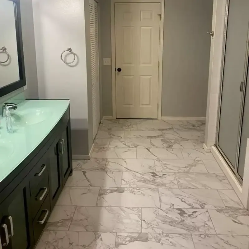 Bathroom with dark vanity, marble-look floor, gray walls, and a white door.