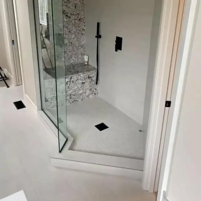 Modern shower with glass door and marble tile.