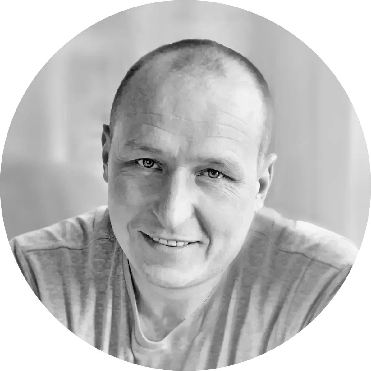 Bald man with a light smile, wearing a gray t-shirt.